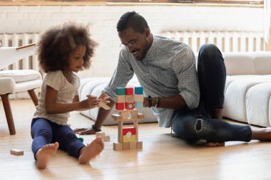 Mutlu baba kızının kule yapmasına yardım ediyor.