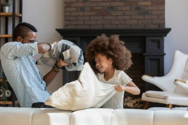 Heyecanlı mutlu baba ve çocuk kanepede yastıklarla kavga ediyor.