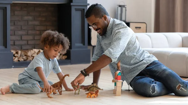 Papai feliz e filho da criança jogando jogos com pequenos dinossauros — Fotografia de Stock
