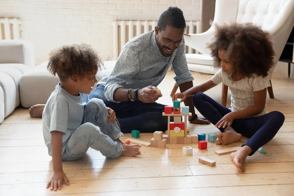 Glücklicher Papa und zwei engagierte Vorschulkinder bauen Turm — Stockfoto