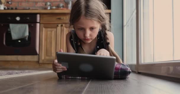 Gelukkig klein schattig meisje met behulp van computer tablet, liggend op de vloer. — Stockvideo