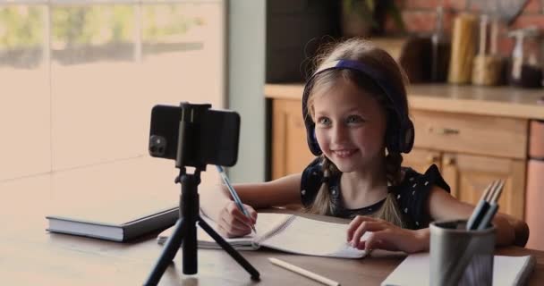 Menina pequena feliz desfrutando vídeo chamada lição usando celular. — Vídeo de Stock