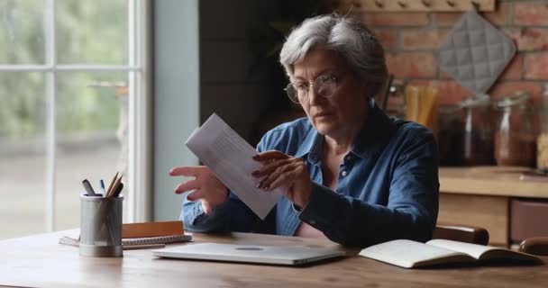 Пожилая женщина читает бумажное письмо, чувствует стресс. — стоковое видео