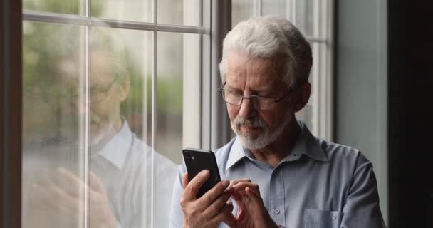 Verträumter alter Mann nutzt Handy-Apps. — Stockvideo