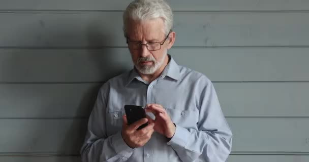 Heureux homme plus âgé dans les lunettes en utilisant smartphone. — Video