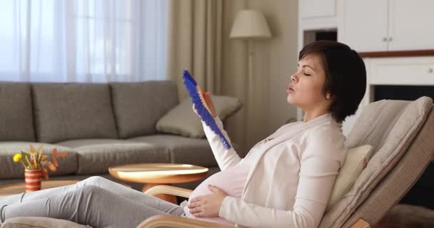 Zwangere vrouw golven fan lijdt aan warmte indoor — Stockvideo