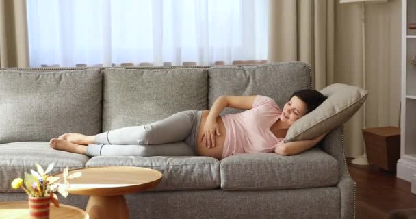 Im gemütlichen Wohnzimmer entspannen auf bequemem Sofa schwangere Frau — Stockvideo