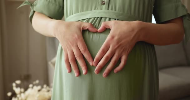 Zwangere vrouw zet armen op grote buik het maken van hart vorm — Stockvideo