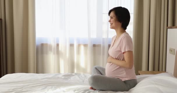 Πλευρά άποψη έγκυος γυναίκα κάθονται στο κρεβάτι εγκεφαλικό επεισόδιο μεγάλη κοιλιά — Αρχείο Βίντεο