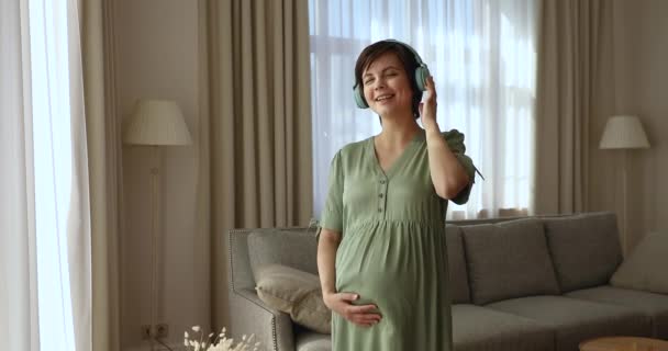 Spokojna kobieta w ciąży nosi słuchawki słucha kojącej muzyki — Wideo stockowe