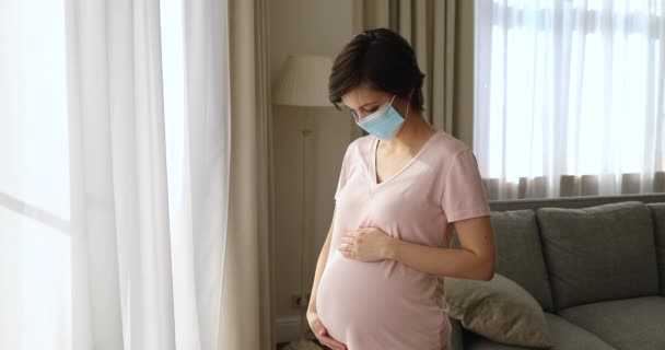 Pregnant woman in protective face mask standing alone indoor — Stock Video