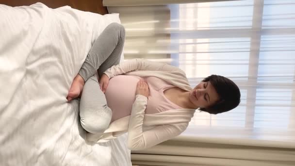 Donna incinta seduta sul letto colpi pancia vista verticale — Video Stock