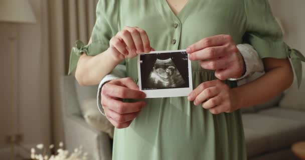 Муж и беременная жена позируют с детским ультразвуковым изображением крупным планом — стоковое видео