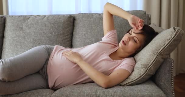 Беременная женщина, лежащая на диване, чувствует себя больной или обеспокоенной — стоковое видео