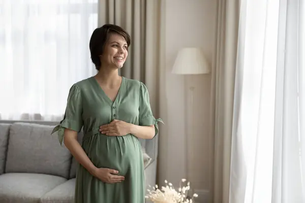 Glad, gravid kvinne se på magen på avstand – stockfoto