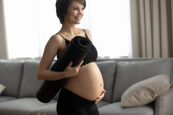 Mosolygó, aktív terhes nő jóga szőnyeggel — Stock Fotó