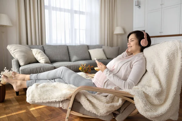 快乐的孕妇在耳机里听音乐 — 图库照片