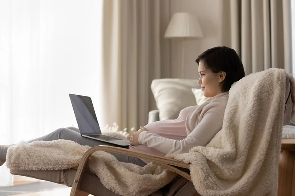 Giovane donna incinta rilassarsi a casa con il computer portatile — Foto Stock