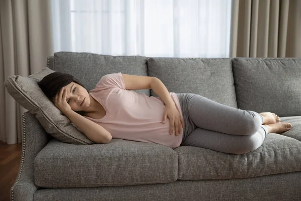 Mulher grávida insalubre deitada no sofá com dor — Fotografia de Stock