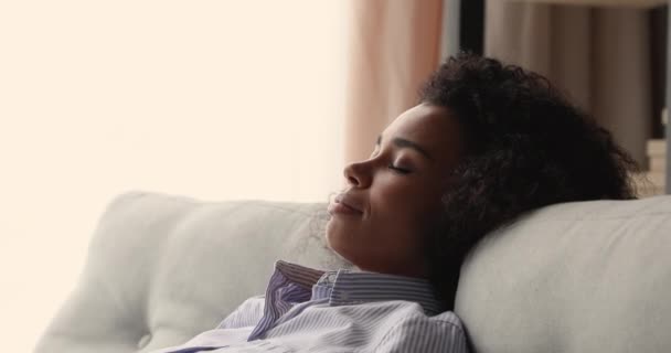Primo piano di una donna africana serena che si rilassa sul divano — Video Stock