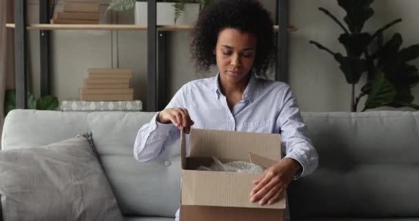 Femme africaine ouvre boîte de colis regarde à l'intérieur se sent satisfait — Video