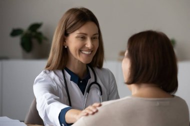 Toplantıda gülümseyen kadın doktor yaşlı hastaya destek oluyor