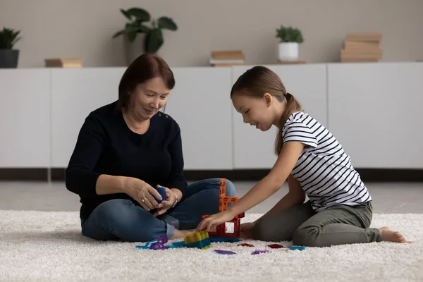 Caring grandmother and small granddaughter play together — Stock Photo, Image