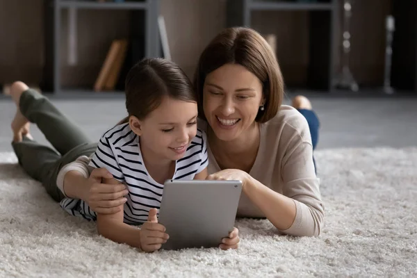 Happy young mom and teen daughter use pad