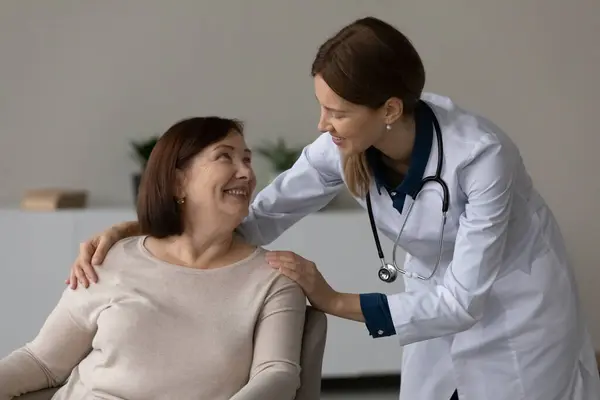 Lachende vrouwelijke verpleegster comfort senior patiënt in het ziekenhuis — Stockfoto