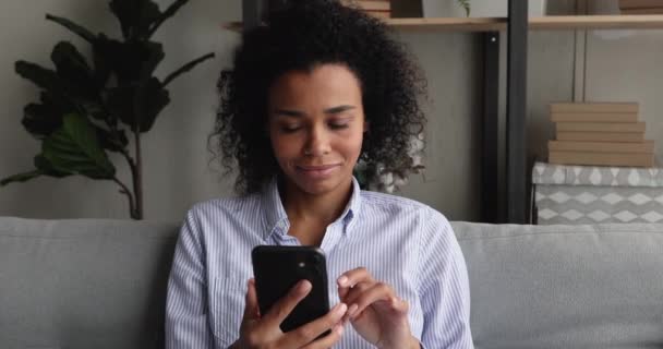 Africana etnia mujer resto en el sofá usando aplicación de teléfono inteligente — Vídeos de Stock