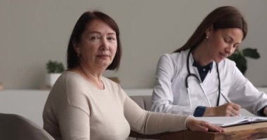 Yaşlı kadın hasta ve doktor klinikte poz veriyor.