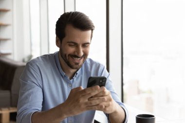 Gülümseyen adam aygıtta cep telefonu tarama interneti kullanıyor