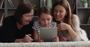 Zeminde tablet cihazıyla üçlü yapan çok nesilli kadın aile.