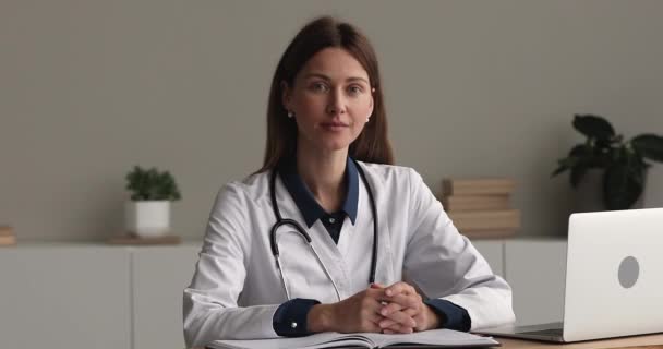 Jovem médica de casaco branco senta-se no local de trabalho — Vídeo de Stock