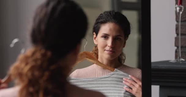 Woman looking in mirror holding blouse choose clothes to wear — Stock Video