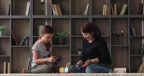 Sevgi dolu büyükanne ve küçük torun evde manyetik yapıcılık oynuyorlar. — Stok video