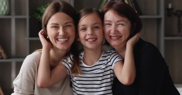 Liten flicka kramar mamma och äldre mormor poserar för kameran — Stockvideo
