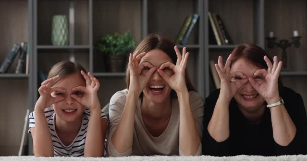 Семья многих поколений весело смеется, делая очки формы с пальцами — стоковое видео