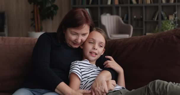 Äldre mormor koppla av på soffan kram prata med lilla barnbarn — Stockvideo