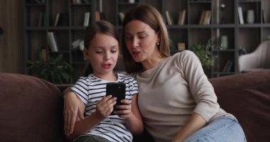 Neşeli küçük kız ve anne modern akıllı telefon kullanarak zaman geçiriyorlar.