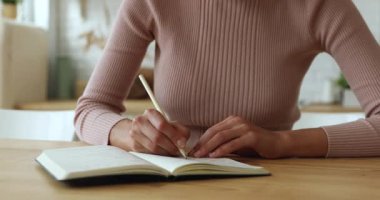 Kadın masada oturup kişisel düzenleyiciyle düşünceler yazıyor.