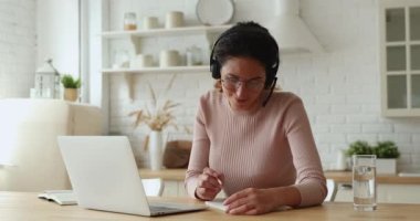 Kulaklık takan kadın bilgi edinmek için evdeki video çağrısını kullan