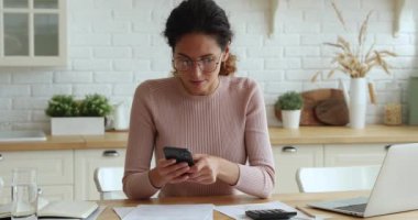 Kadın hesaplamalar yapar, faturaları akıllı telefondaki banka uygulaması ile öder.