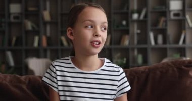 Kız kanepede oturur kameraya bakar video konferansı boyunca konuşur.