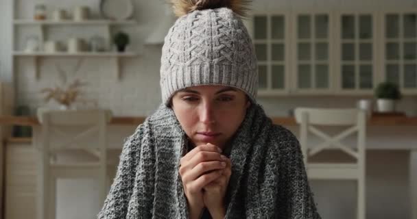 Frozen woman sits at home wrapped in plaid wearing hat — Stock Video