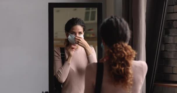 Женщина перед уходом из дома надеть хирургическую маску для лица — стоковое видео