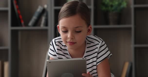 Close-up kleine 8s meisje liggen indoor met tablet apparaat — Stockvideo