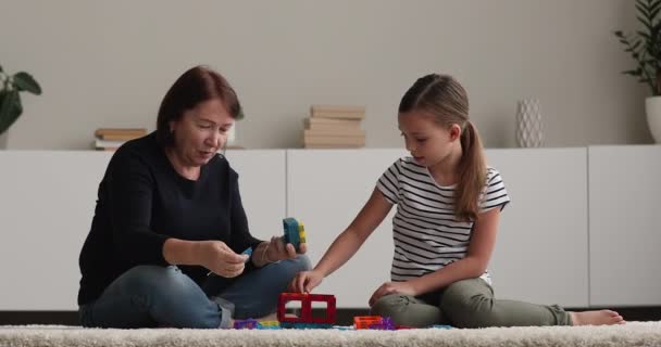 Літня 50-річна бабуся і маленька онучка грають разом з магнітним конструктором — стокове відео