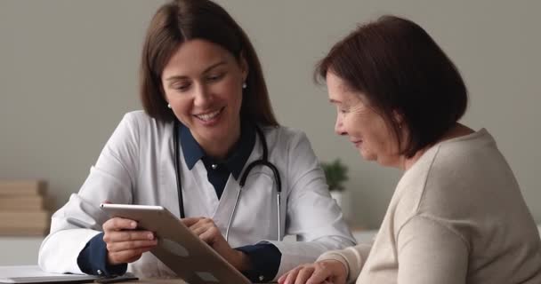 Médico explicar a los pacientes mayores resultado de la prueba médica en la tableta — Vídeo de stock