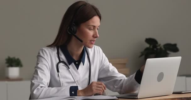 Doctor desgaste auriculares haciendo videollamada en el ordenador portátil — Vídeo de stock